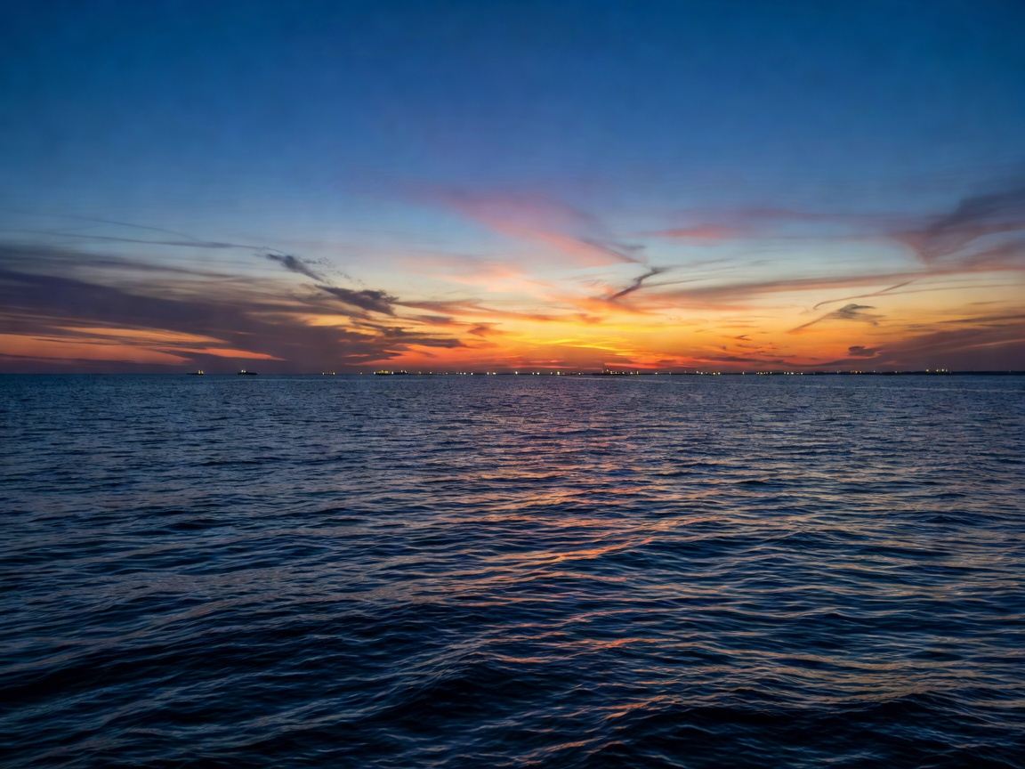 Beautiful dark blue sea sunset with distant lights